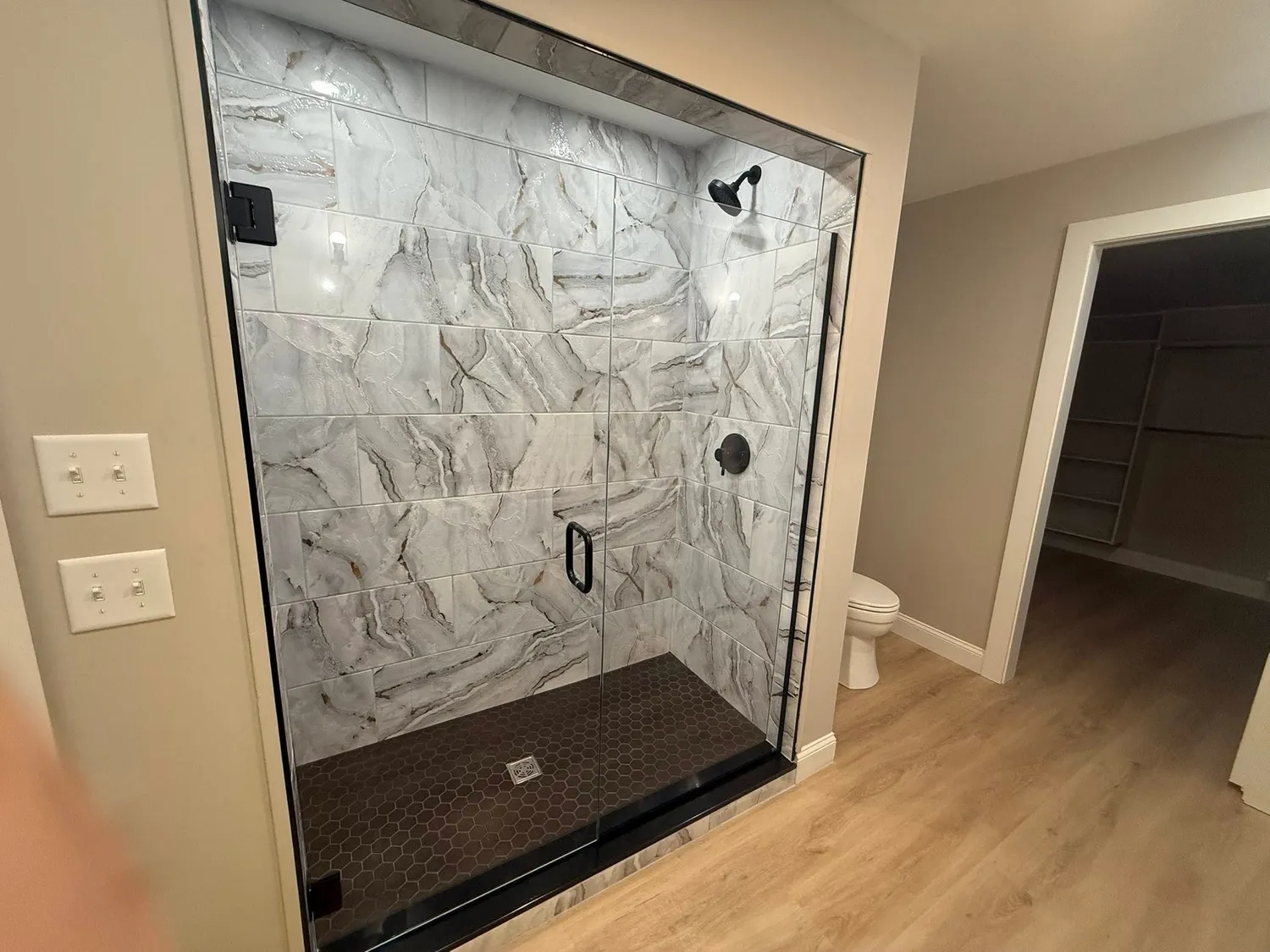 Frameless glass shower enclosure with marble surround