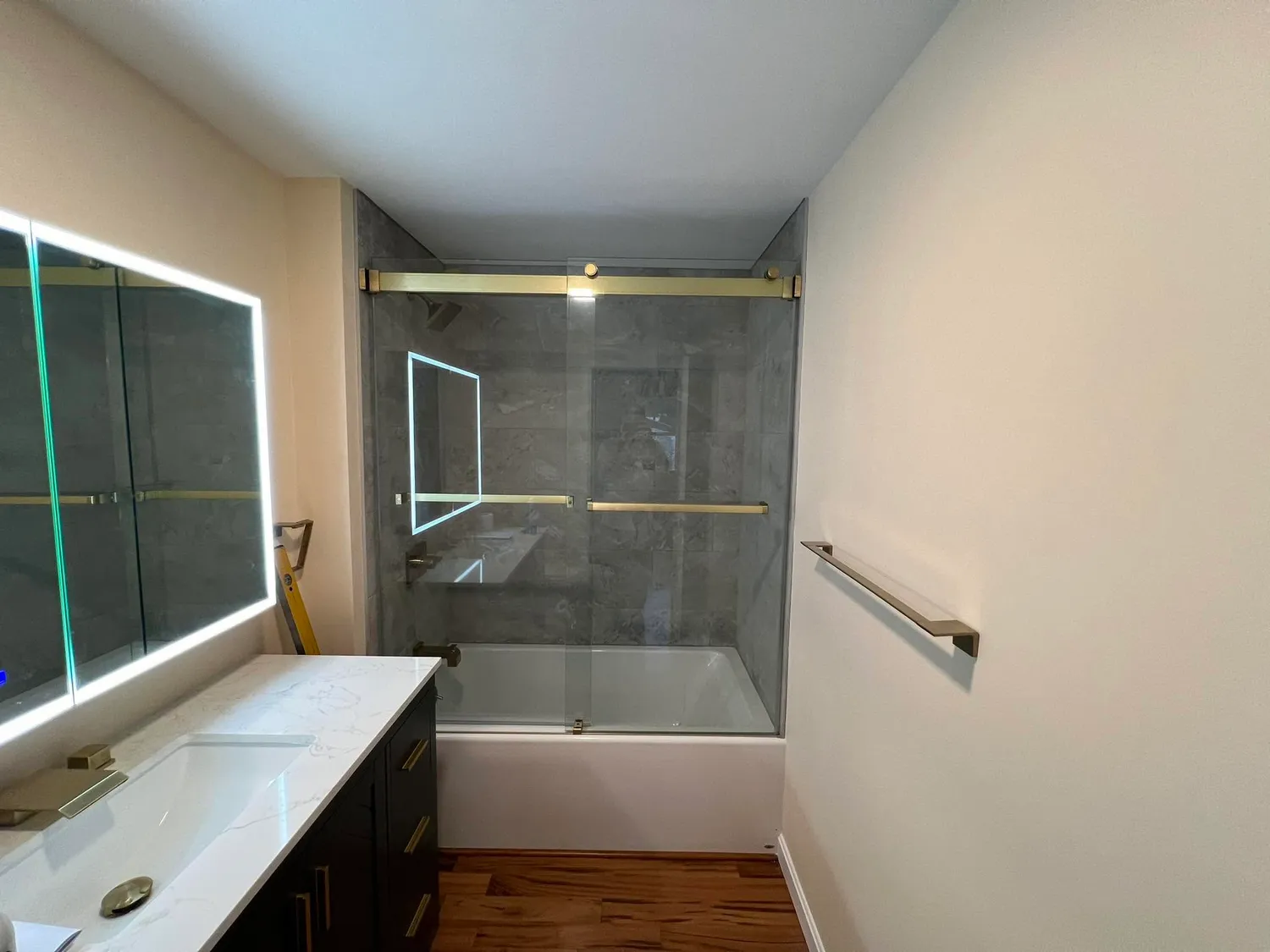 Modern tub shower with gold hardware and frameless glass
